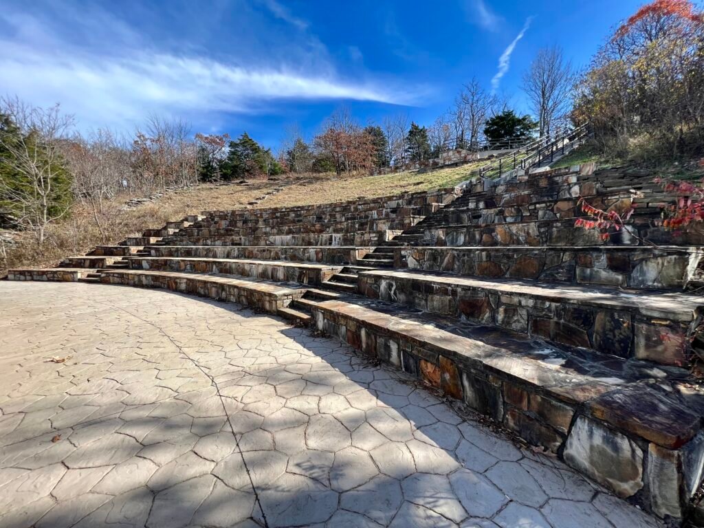 Stone amphitheater at Mount Magazine State Park with tiered seating under a bright blue Arkansas sky.