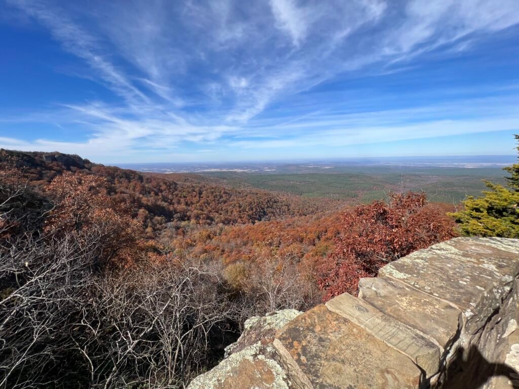 Panoramic fall view from the Mount Magazine amphitheater overlooking colorful forest and distant Arkansas valley.