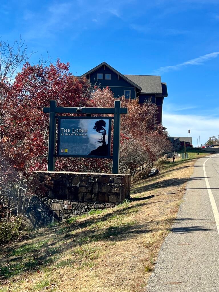The Lodge at Mount Magazine State Park surrounded by fall foliage under a bright blue sky.
