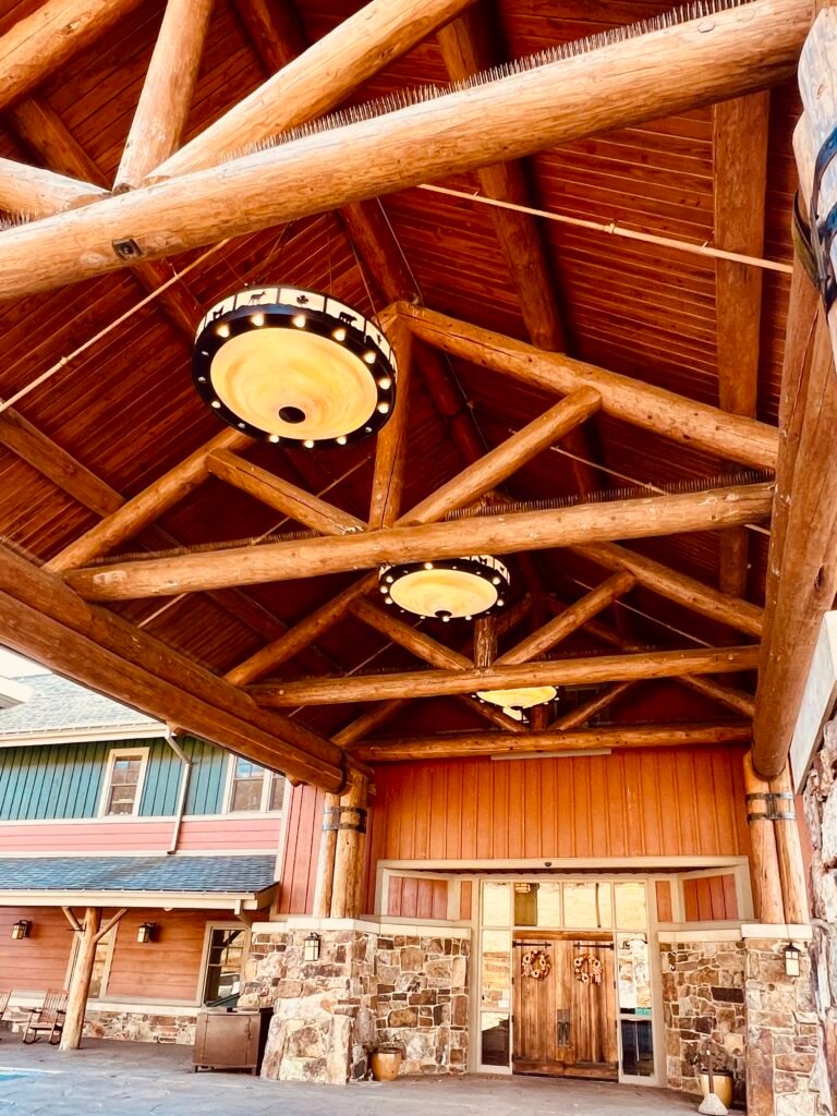 Timber-framed entrance to The Lodge at Mount Magazine with stone columns and autumn foliage.