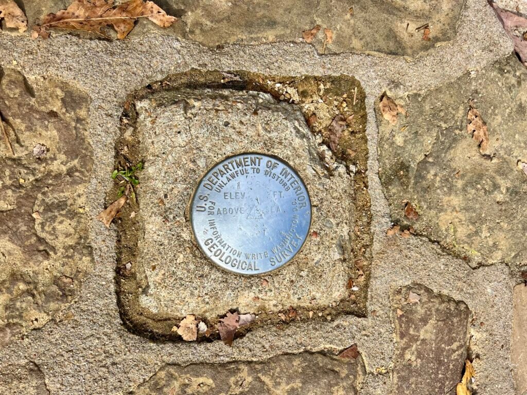 U.S. Geological Survey benchmark marker embedded in stone at the Mount Magazine summit.