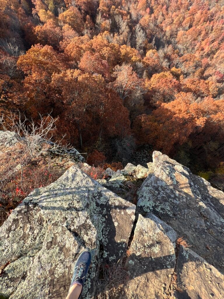 Steep rocky cliff at Inspiration Point overlooking a deep valley of colorful fall foliage at Mount Magazine State Park.