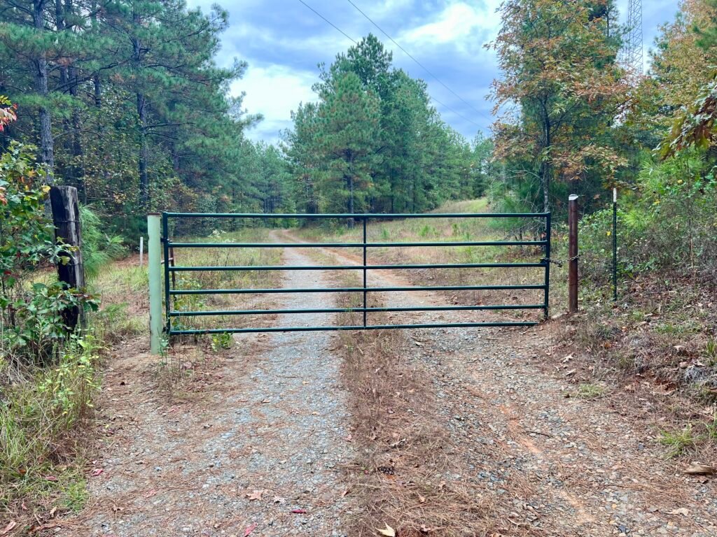 Metal gate across a dirt road marking the start of the Driskill Mountain trail in Kisatchie National Forest.