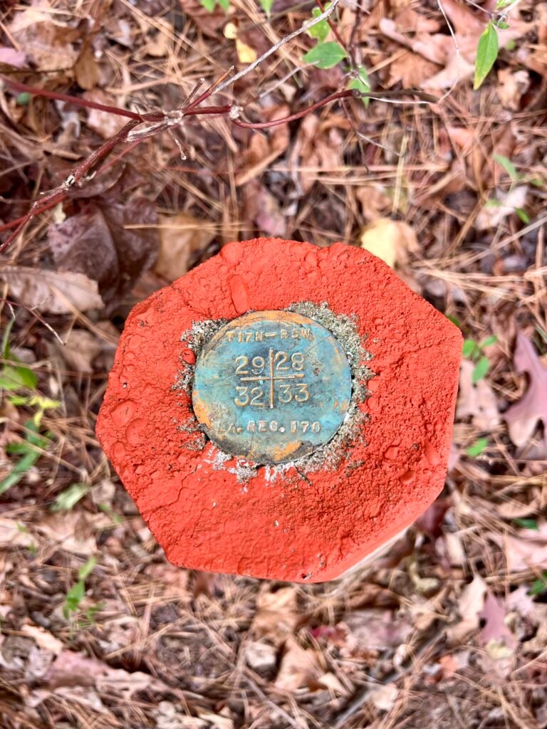 Close-up of painted red survey marker with brass longitude and latitude disk on Driskill Mountain