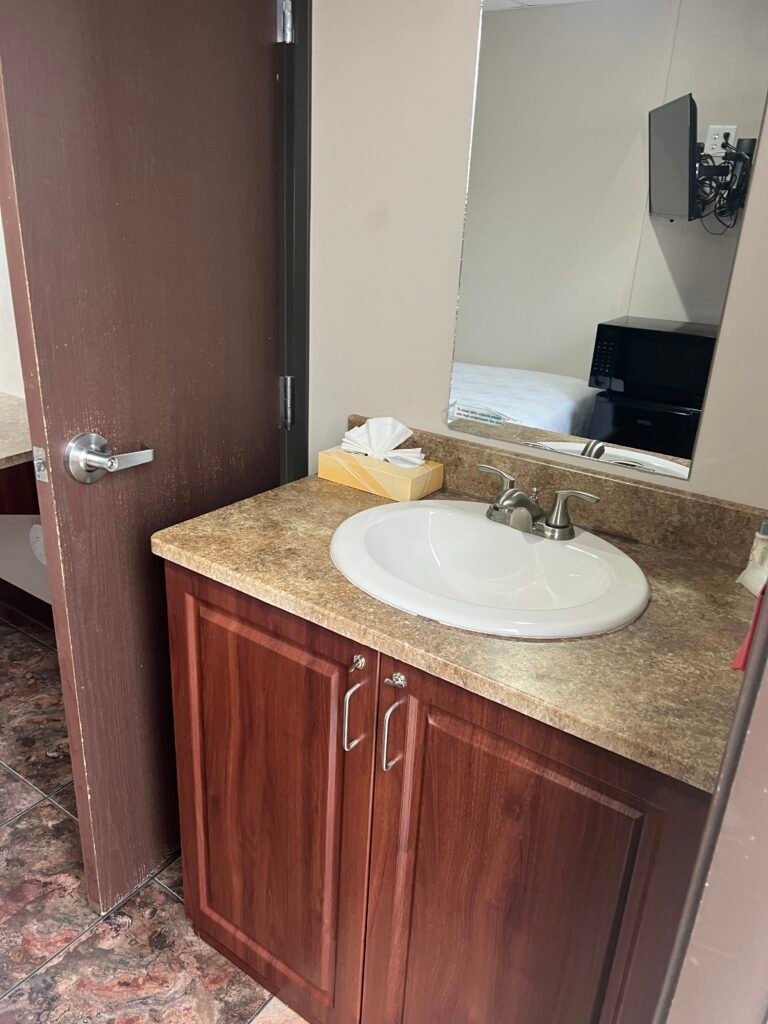 Bathroom vanity with sink and mirror inside a Karbani Inn guest room in Carlsbad, New Mexico.