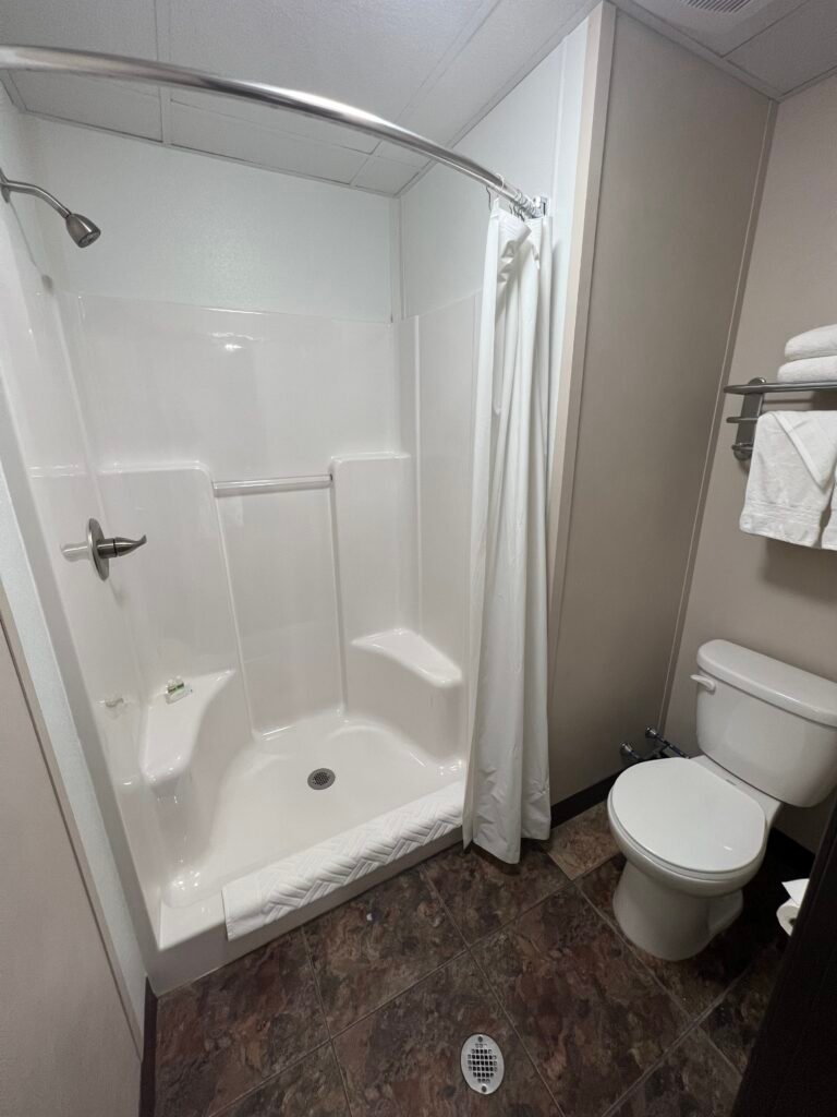 Compact bathroom with shower and toilet inside a Karbani Inn modular hotel room.