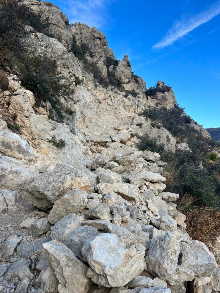 Narrow rocky trail hugging limestone cliffs just before rounding the backside of Guadalupe Peak in Texas.