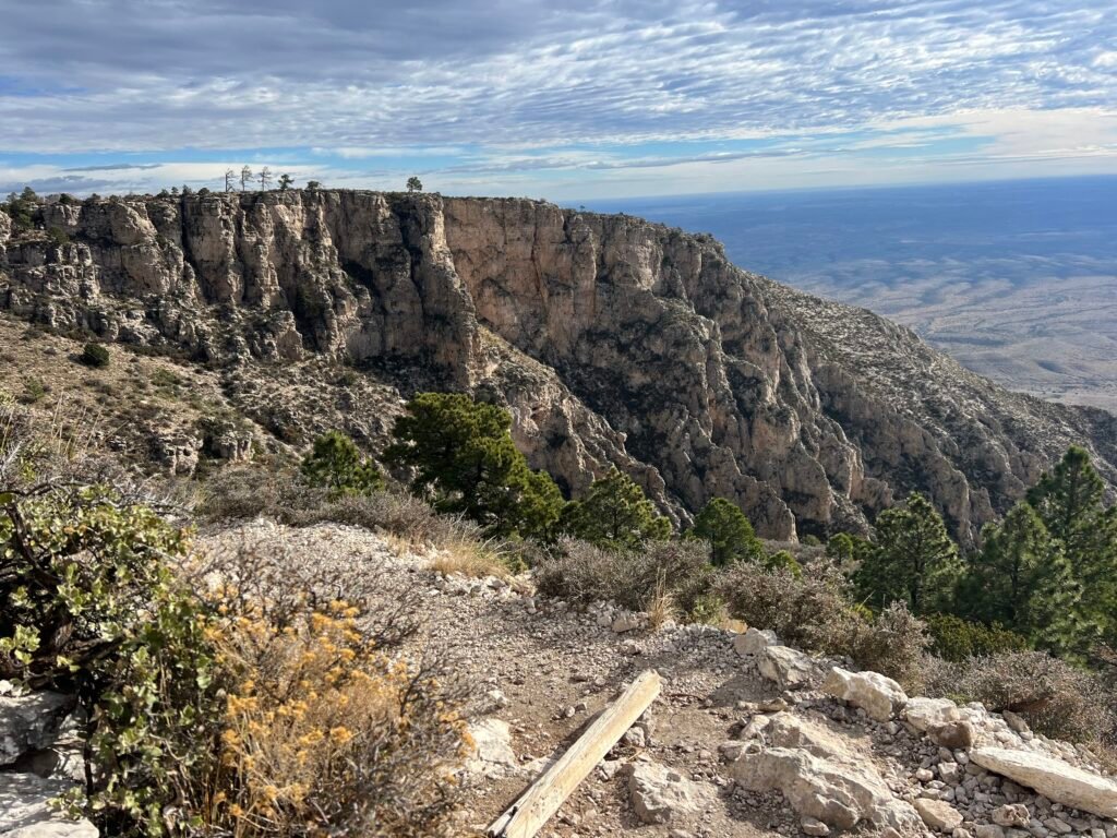 Cliffside view along Guadalupe Peak trail with dramatic limestone walls and desert valley below