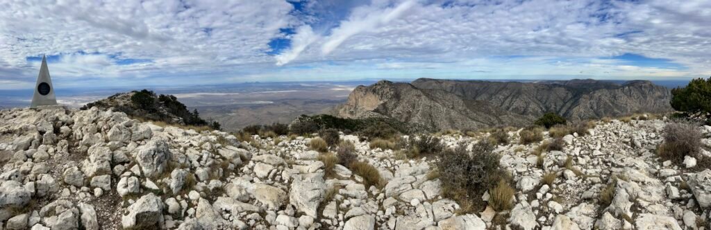Panoramic view from Guadalupe Peak summit with stainless steel monument and rugged desert mountains below