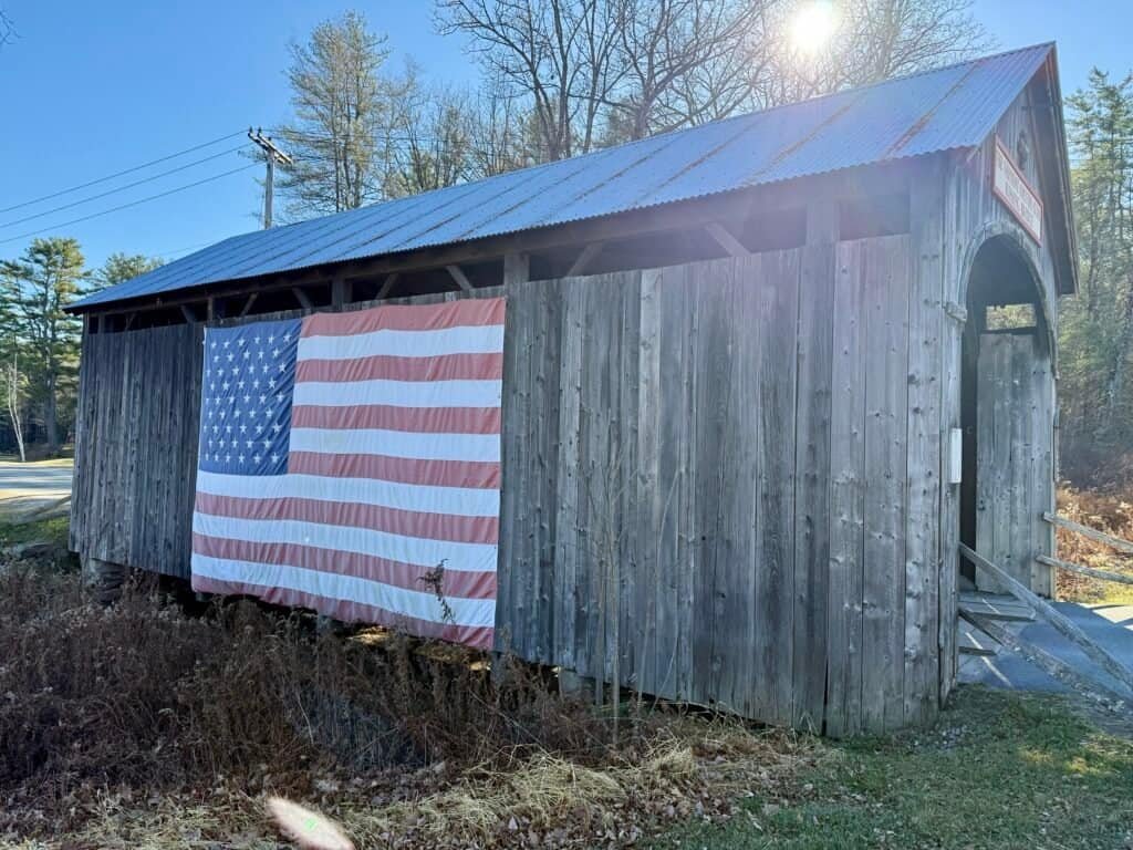 Covered wooden kissing bridge at The Vermont Country Store in Bellows Falls, Vermont, decorated with a large American flag.