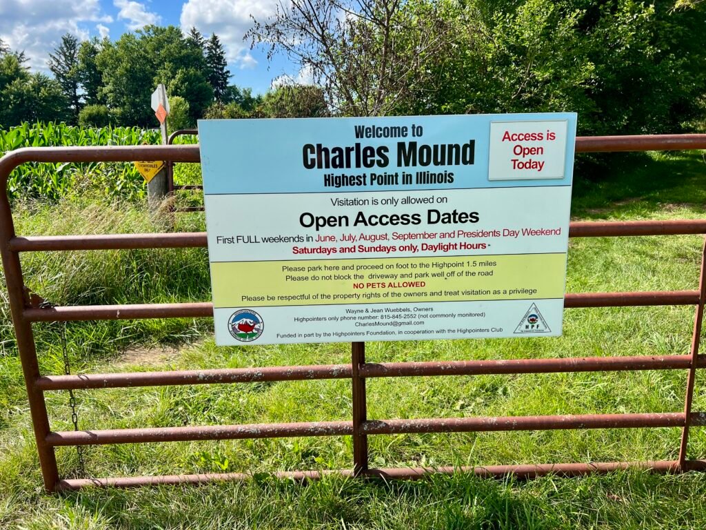 Charles Mound trailhead sign on a farm gate showing open access dates and visitation rules in Illinois.