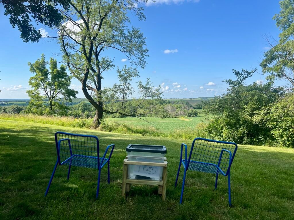 Blue chairs and summit log bin overlooking rolling Illinois farmland at Charles Mound.