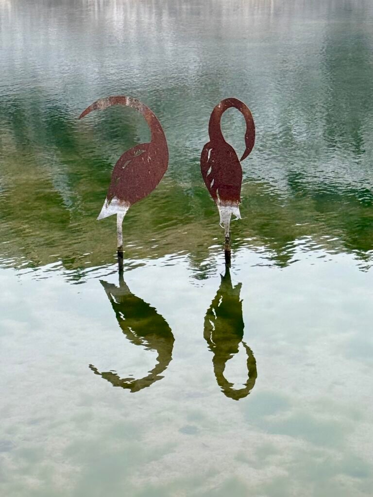Metal bird statues standing in shallow spring water at Big Springs in Kansas.
