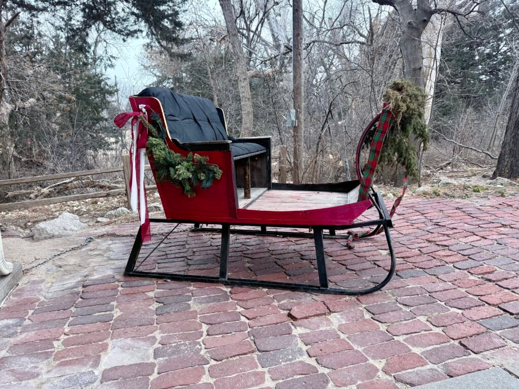 Red vintage sleigh displayed outside the Steele Home Museum at Historic Lake Scott State Park