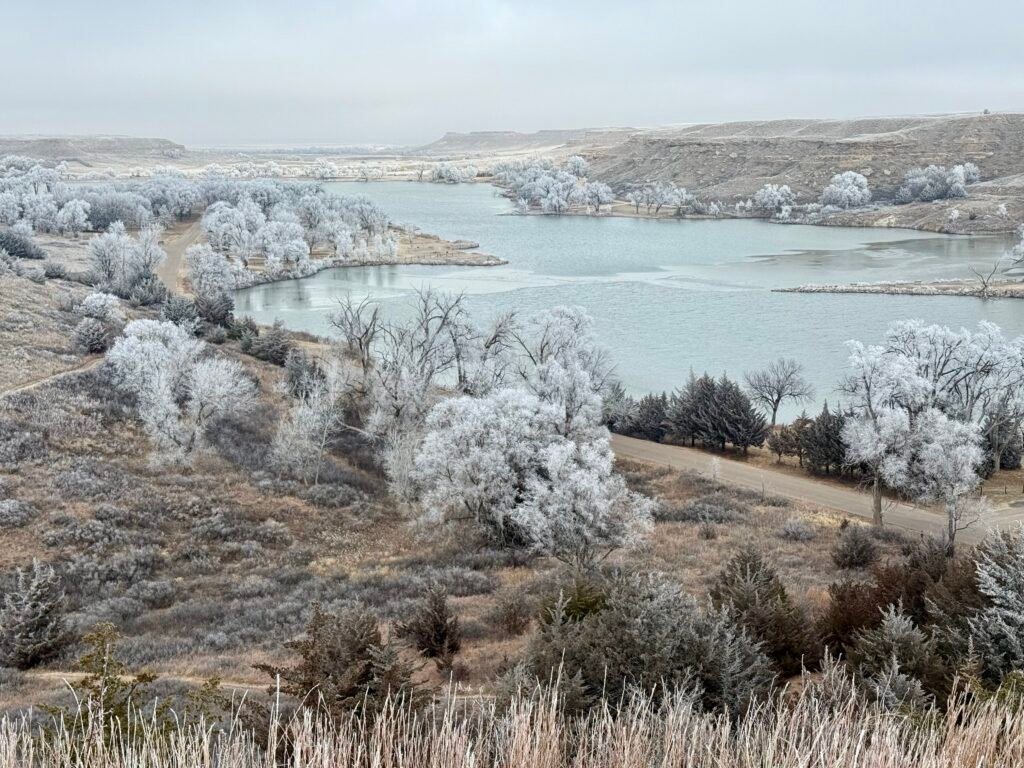 View of Lake Scott from Buzzard’s Point, with frost-covered trees lining the shoreline and rolling Kansas hills in the background.