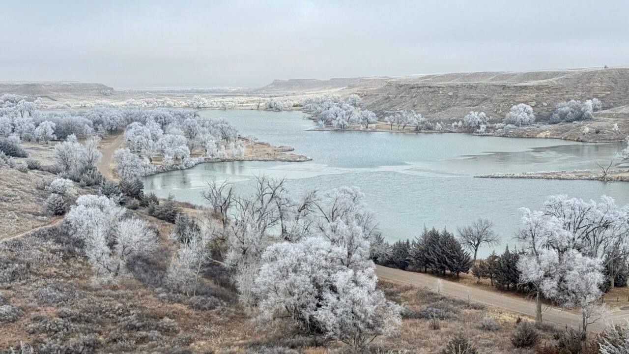 Winter view of Historic Lake Scott in western Kansas with frost-covered trees and partially frozen lake.