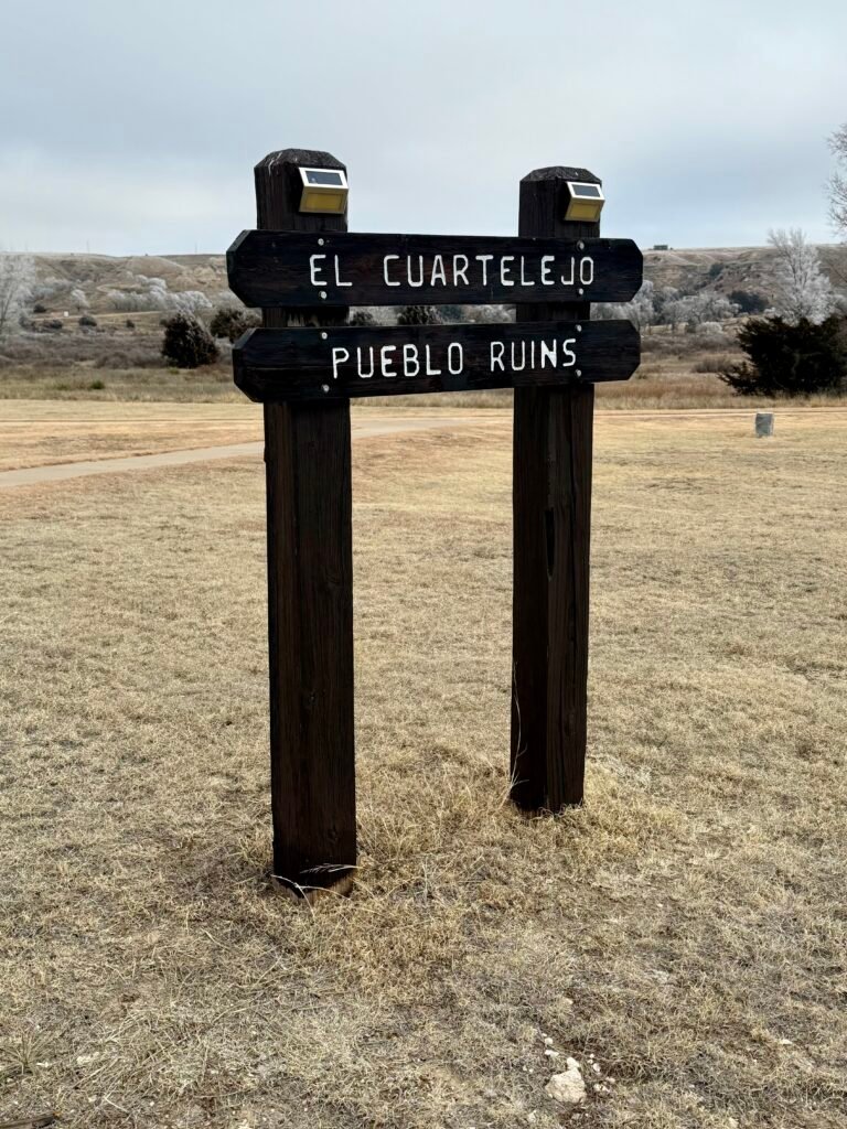 Wooden sign reading “El Cuartelejo Pueblo Ruins” at the parking area near Lake Scott State Park.