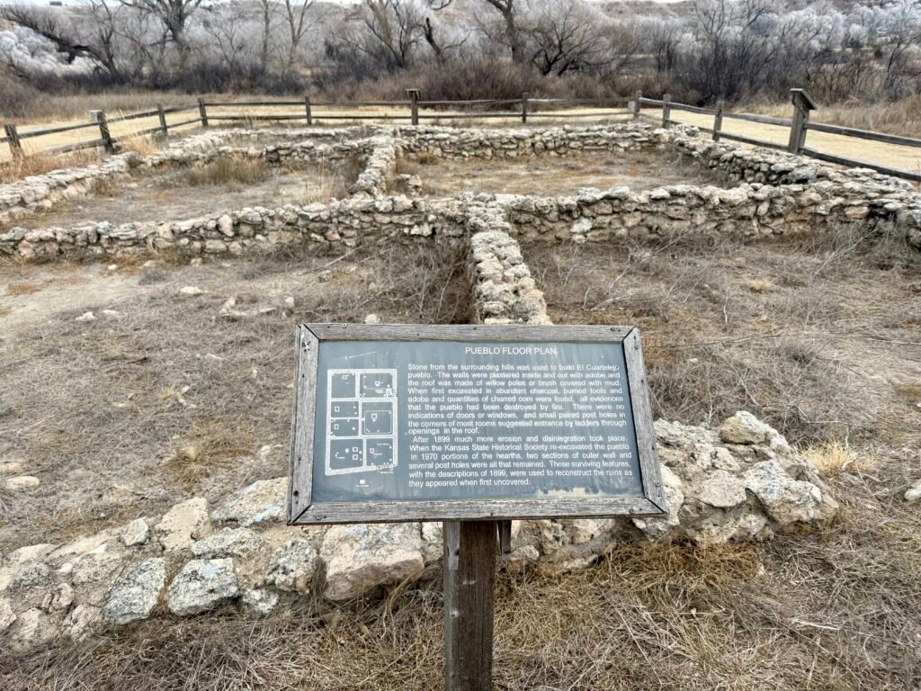 Interpretive sign showing the pueblo floor plan in front of the reconstructed stone foundations at El Cuartelejo.
