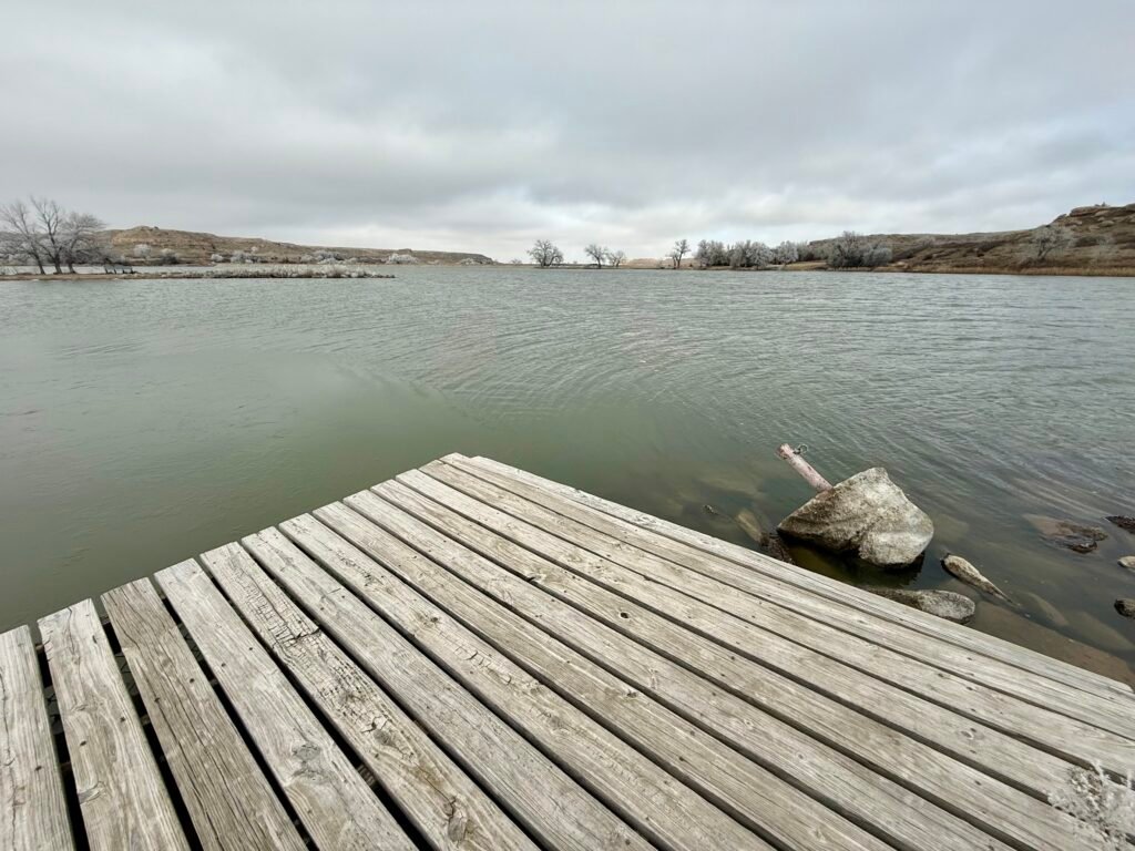 Wooden dock extending into Lake Scott under gray winter skies, with rolling hills and leafless trees in the distance.