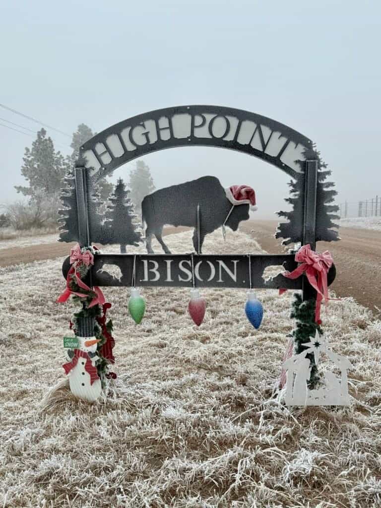 High Point Bison Ranch welcome sign decorated for winter along a foggy dirt road near Panorama Point, Nebraska.