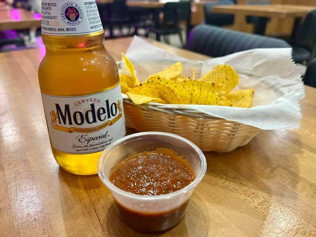 Bottle of Modelo Especial with basket of tortilla chips and salsa on a restaurant table
