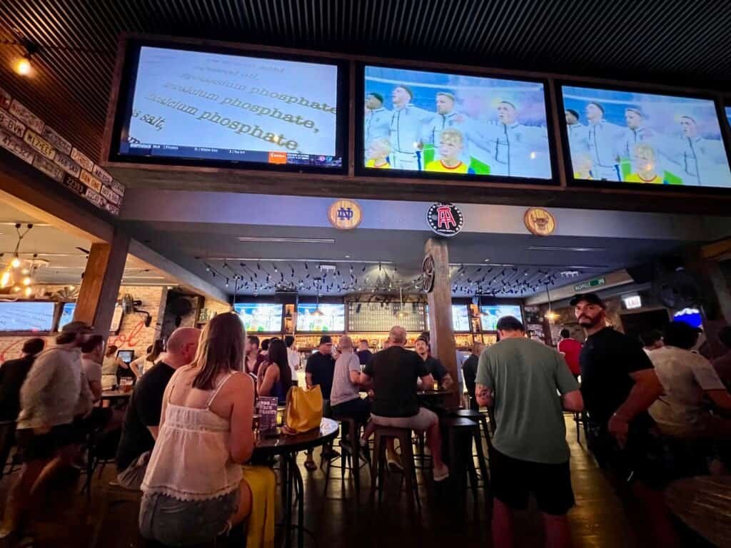 Crowd watching a game inside Barstool River North with multiple TVs and bar seating.