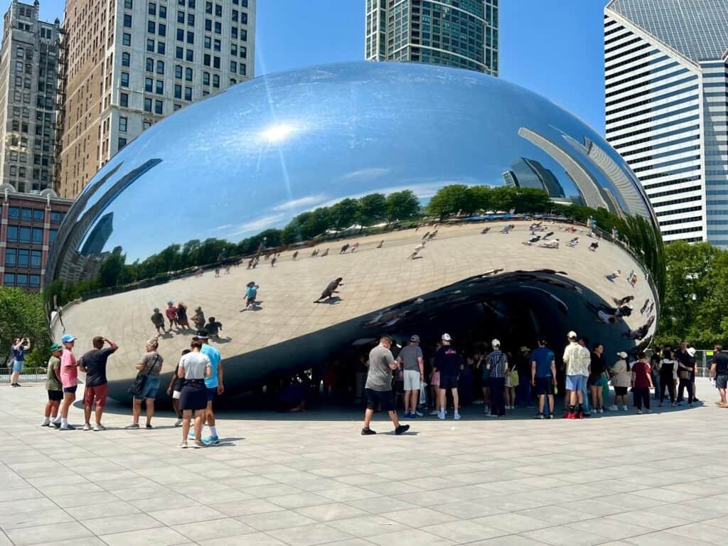 Visitors gathered beneath Cloud Gate reflecting Chicago’s skyline in Millennium Park