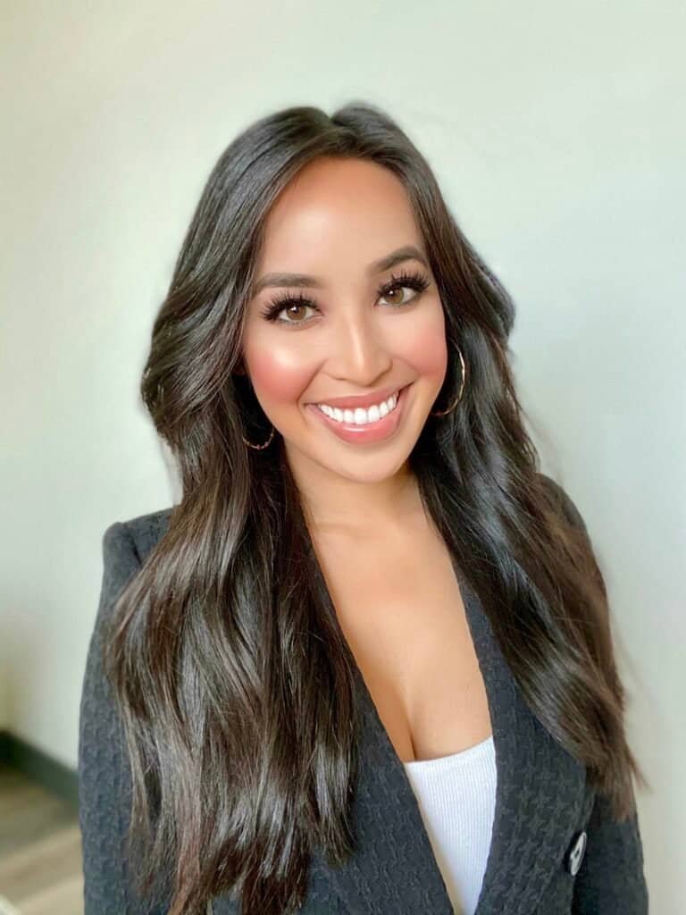 Portrait of Lan Ho smiling, wearing a black blazer against a neutral background