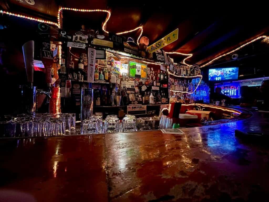 Dimly lit bar interior at Rossi’s with string lights and a crowded back bar