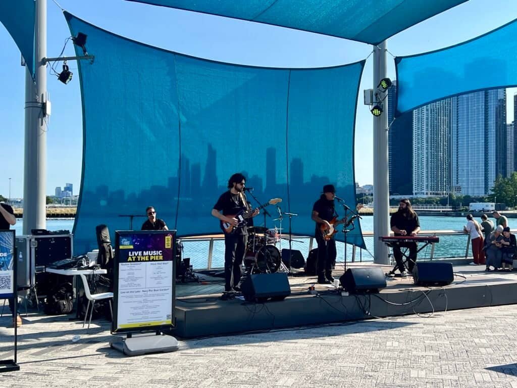 Almafuerte performing live music at Navy Pier with the Chicago skyline behind the stage