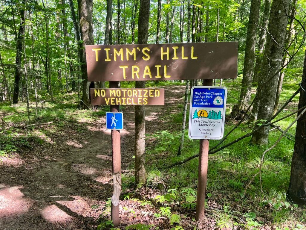 Timms Hill Trail sign with no motorized vehicles notice at wooded trailhead in Wisconsin.