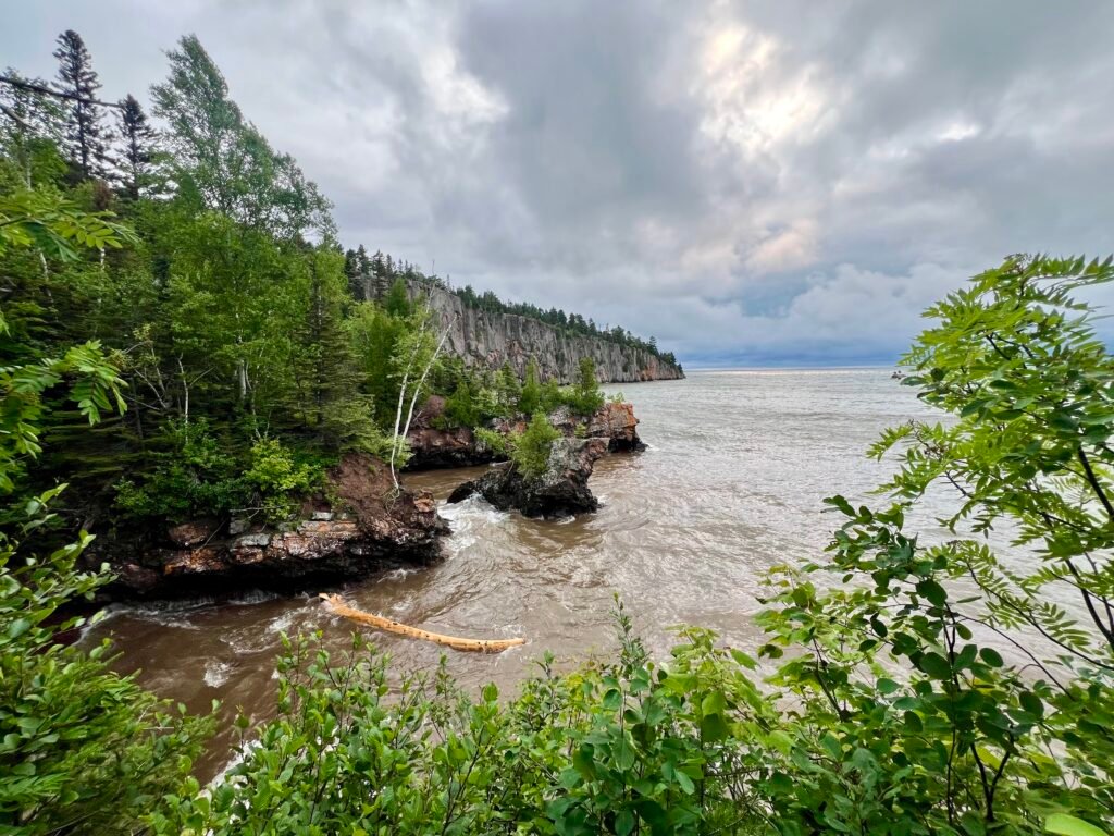 Stormy waves of Lake Superior crashing below the cliffs at Tettegouche State Park, tossing a large log in the surf.