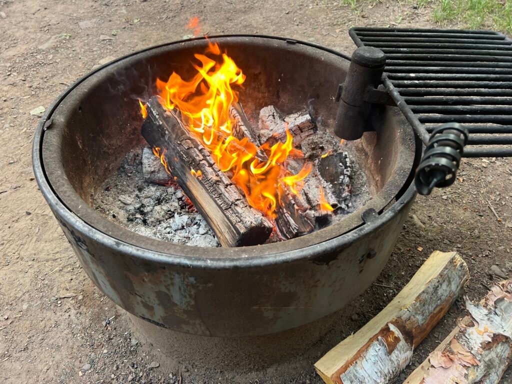 Campfire burning in a metal fire ring at a Tettegouche State Park campsite.