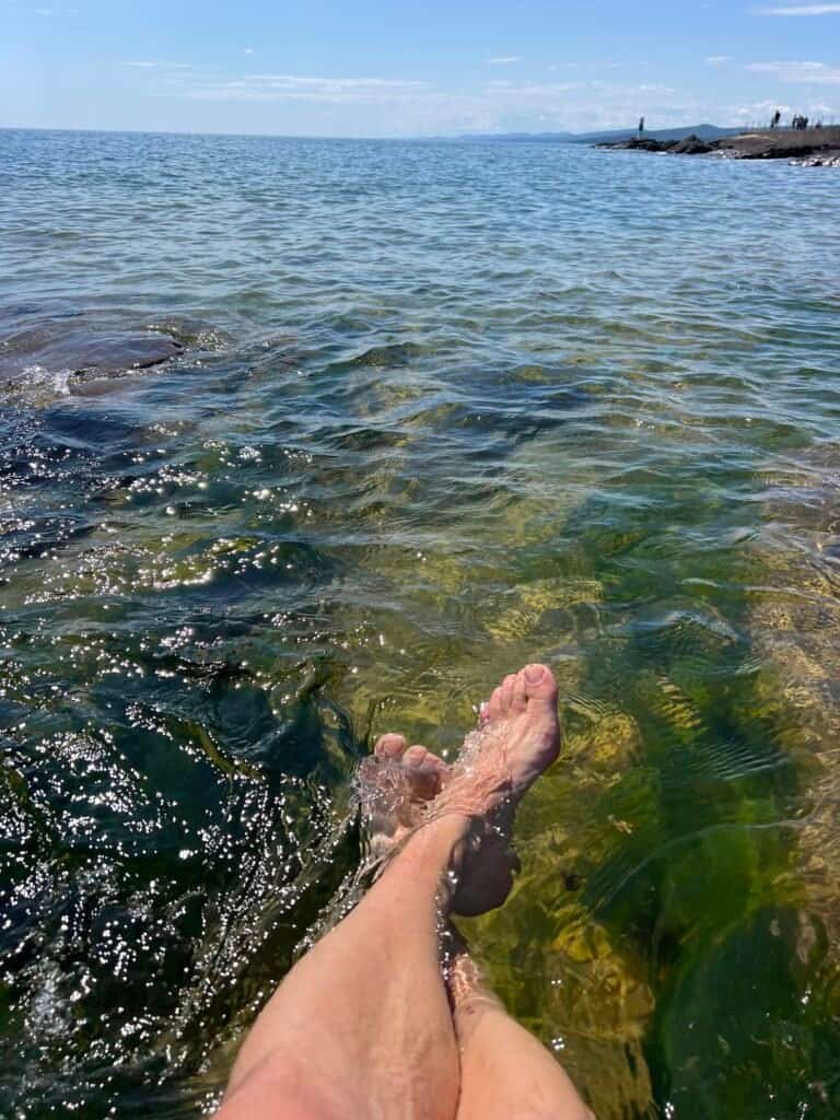 Bare feet cooling off in the clear waters of Lake Superior near the rocky shoreline