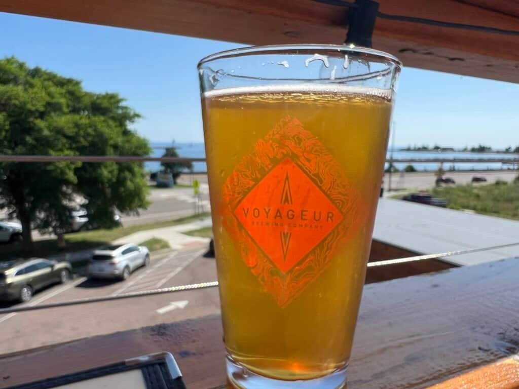 Pint of beer from Voyageur Brewing Company on an outdoor deck overlooking Lake Superior in Grand Marais.