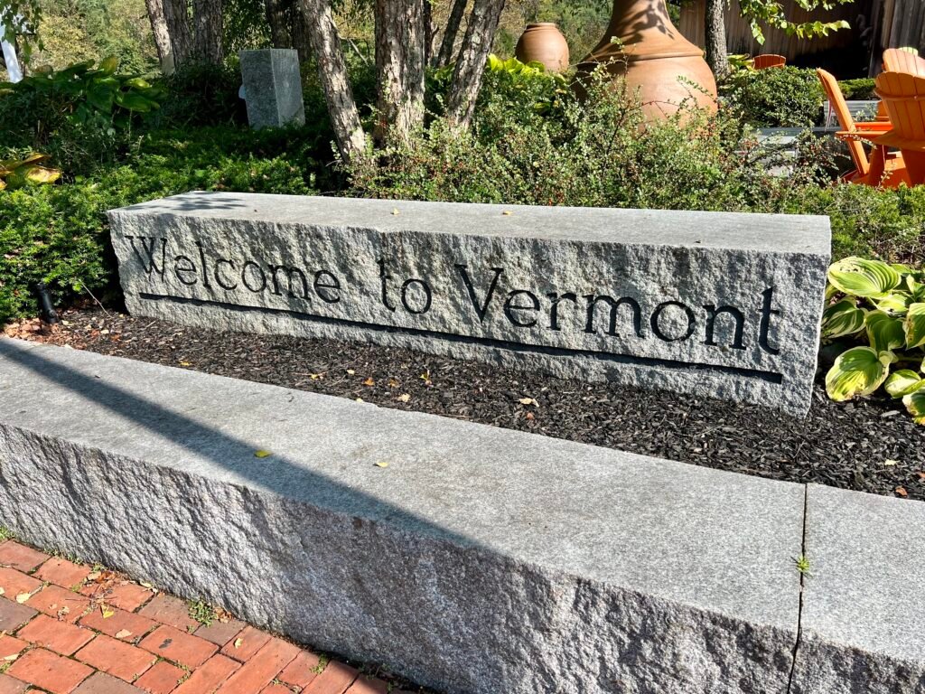 Stone “Welcome to Vermont” sign at the Guilford Welcome Center surrounded by landscaped gardens.
