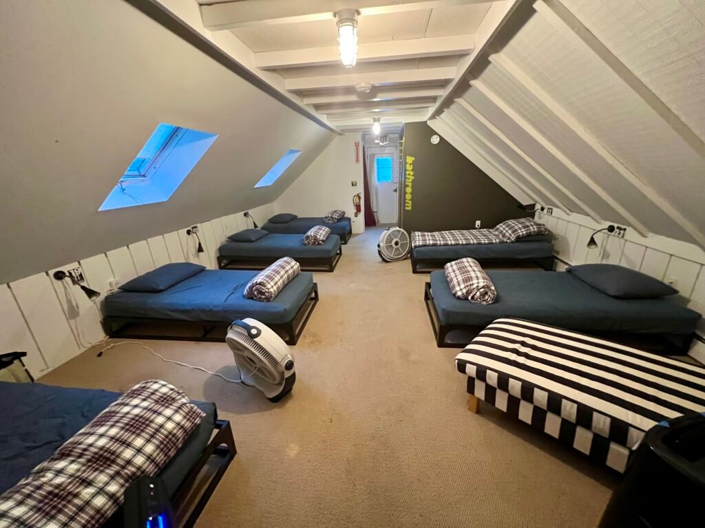 Shared dorm room at Hostel Tevere with multiple single beds under a sloped ceiling in Vermont.