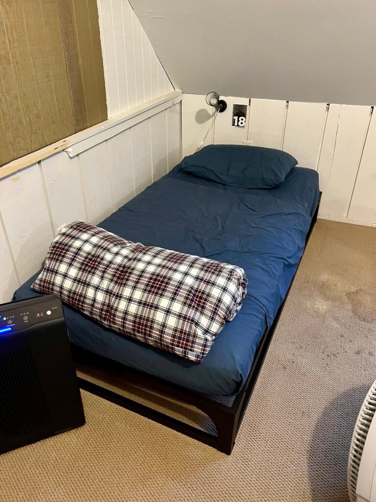 Single bed with blue bedding labeled number 18 inside the Hostel Tevere dorm room.