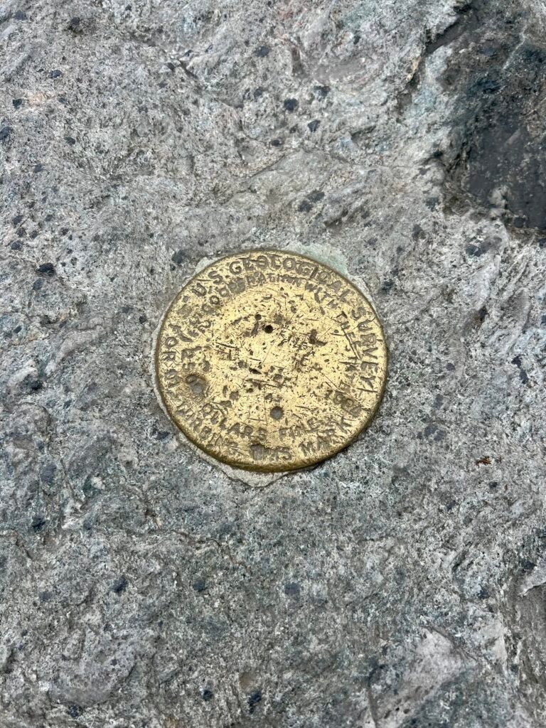 U.S. Geological Survey benchmark marker embedded in rock near the Mount Mansfield summit.