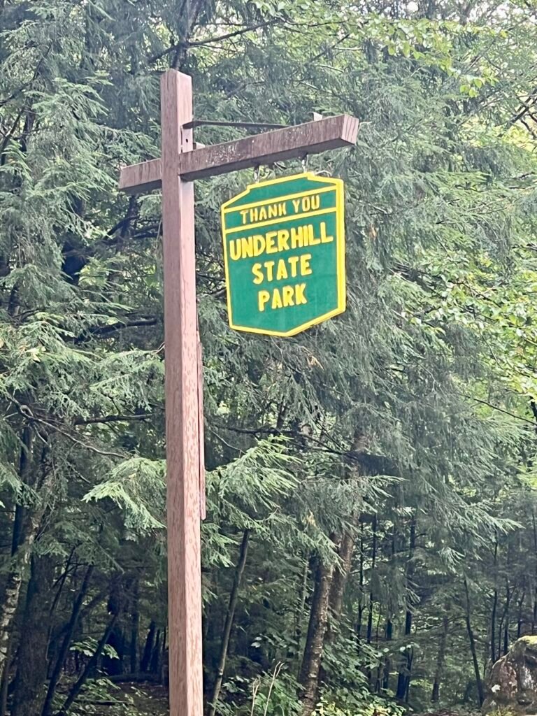 Thank You Underhill State Park sign hanging on a wooden post in a forest setting.
