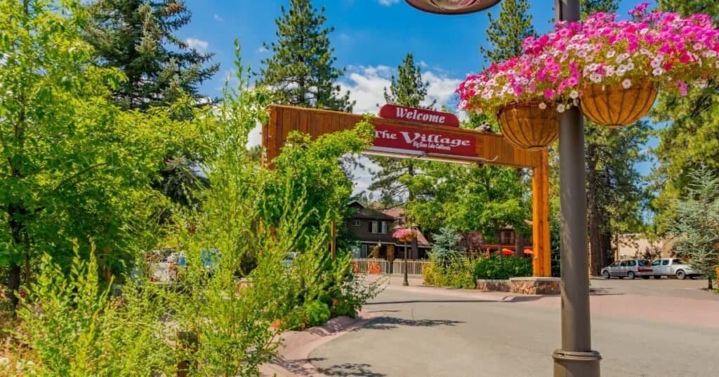 Entrance to Big Bear Lake Village surrounded by pine trees and summer flowers