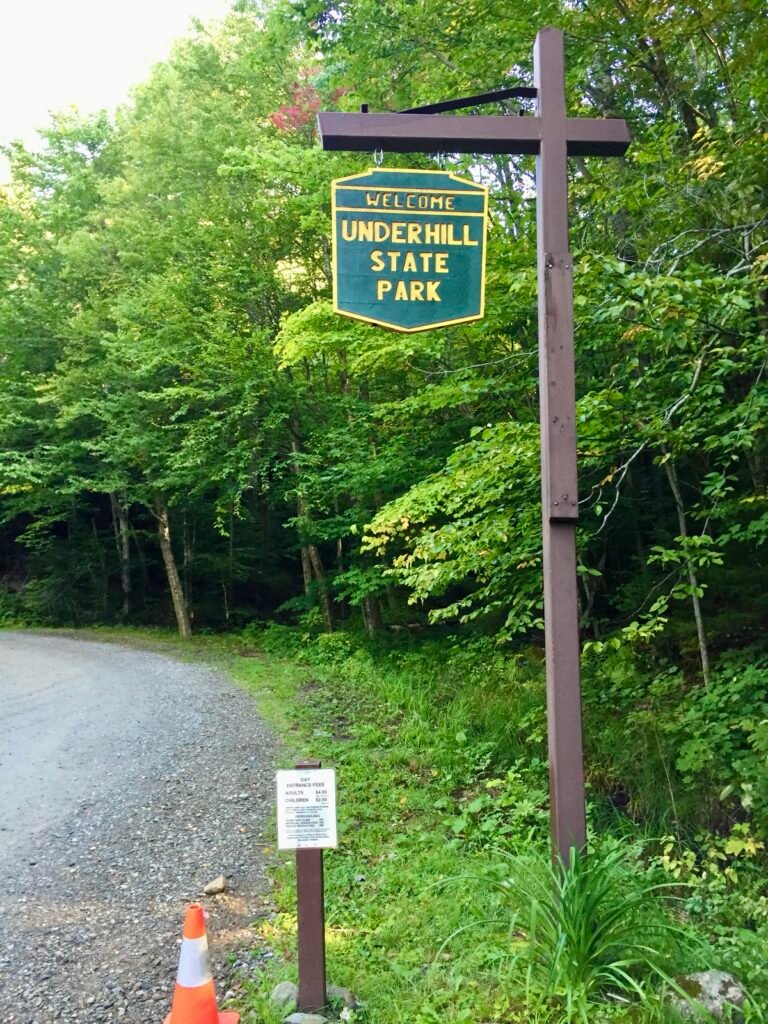 Welcome sign for Underhill State Park along a wooded roadside in Vermont.