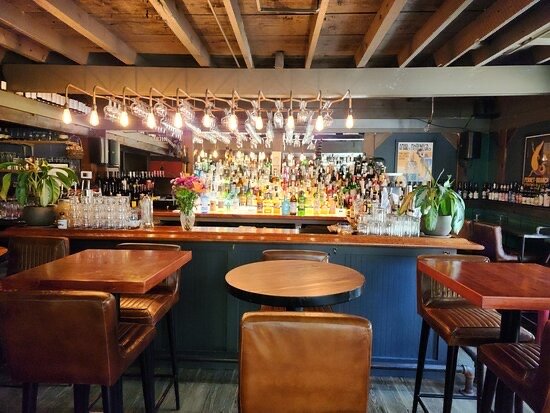 Cozy bar area at Déco restaurant inside Hostel Tevere with wood beams and bottle-lined shelves.
