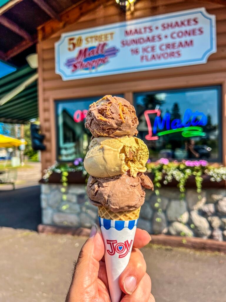 Triple-scoop waffle cone held in front of 5th Street Malt Shoppe in Two Harbors.