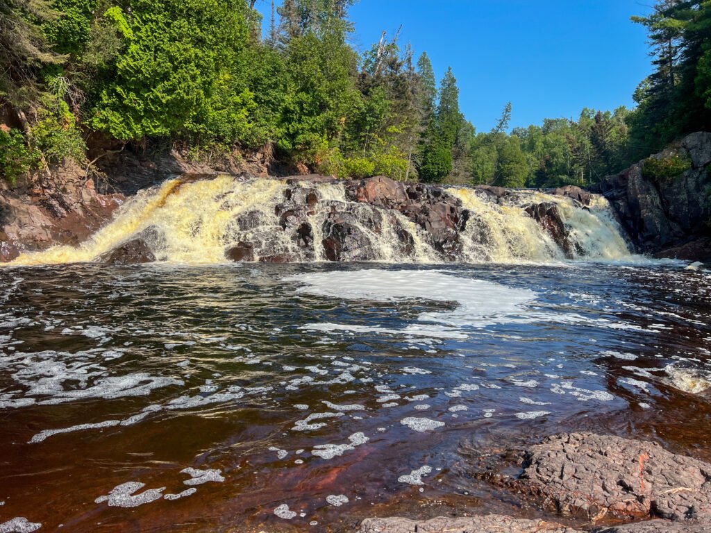 Close-up view of Two Step Falls cascading over dark rock ledges in Tettegouche State Park, Minnesota.