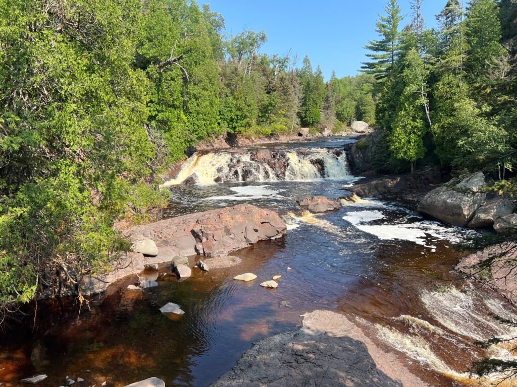 Two Step Falls flowing over rocky ledges along the Baptism River in Tettegouche State Park, Minnesota.