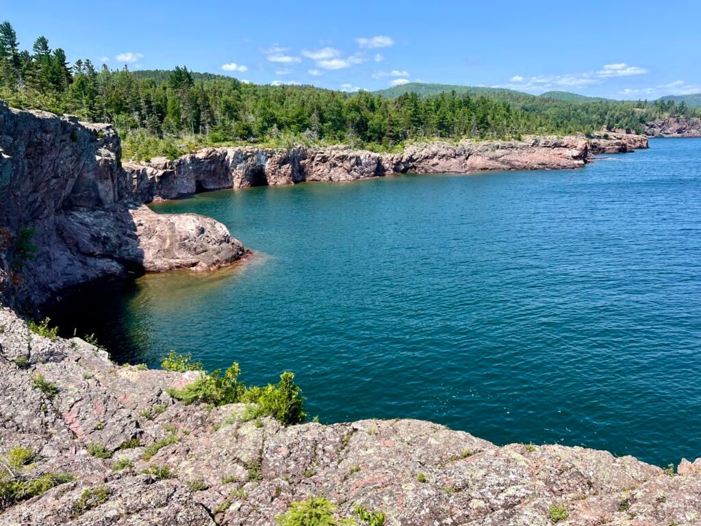Calm turquoise waters of Lake Superior meeting rugged cliffs along Minnesota’s North Shore.