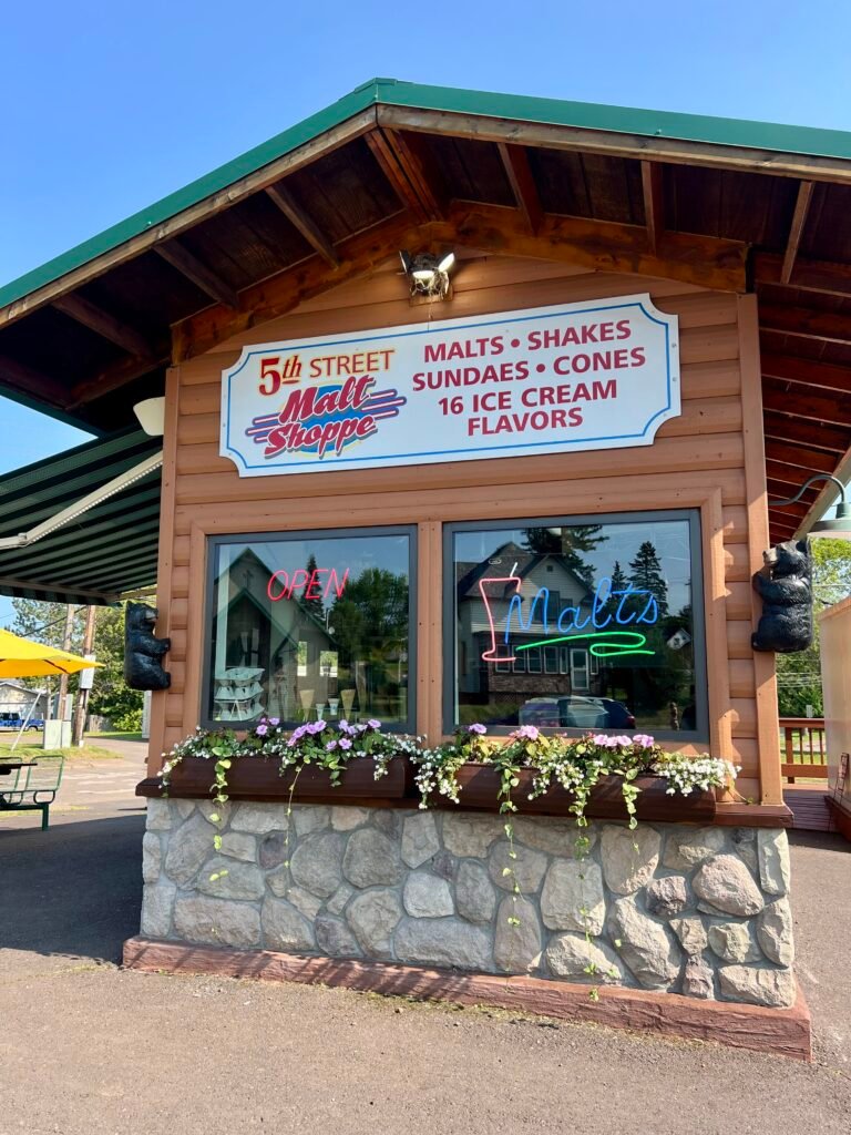 Exterior of 5th Street Malt Shoppe in Two Harbors, Minnesota, with neon “Malts” sign in the window.
