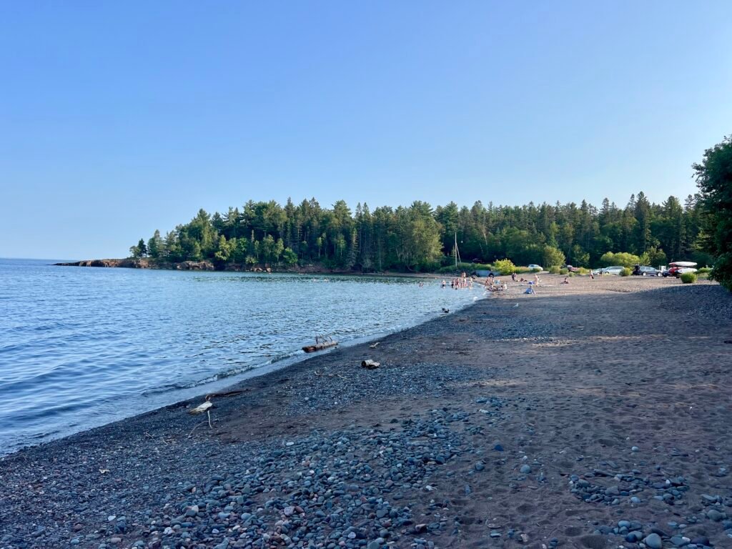 Pebbly beach along Lake Superior in Two Harbors with families enjoying the shoreline.