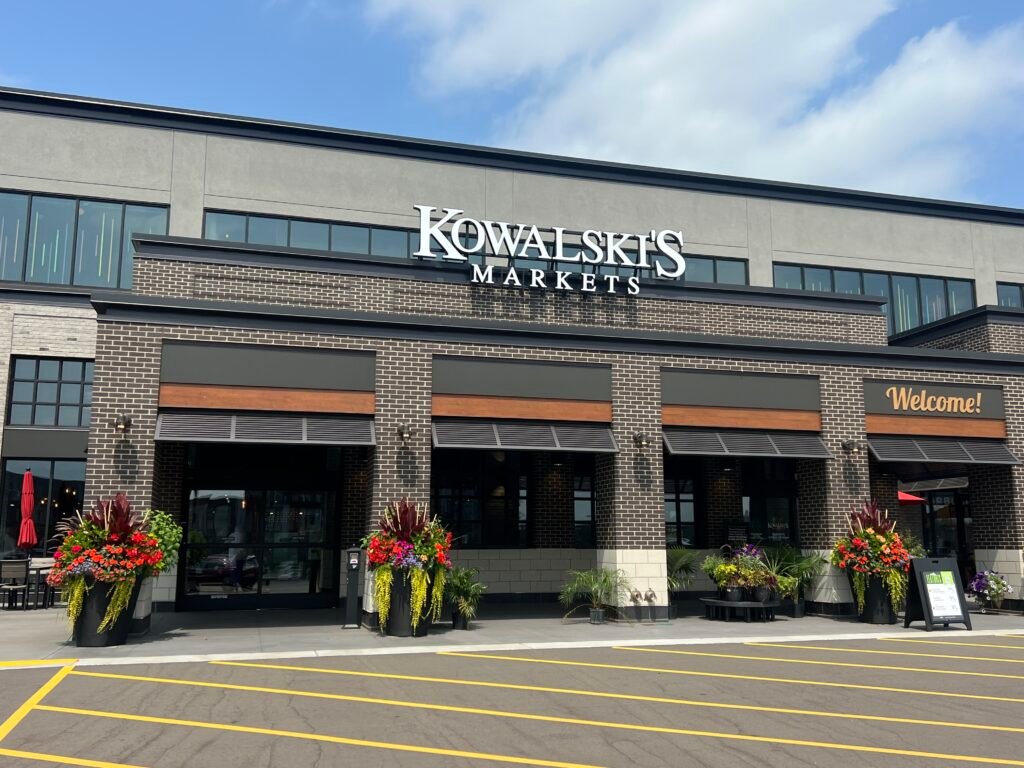 Exterior of Kowalski’s Market in Minneapolis with large storefront sign and flower planters.